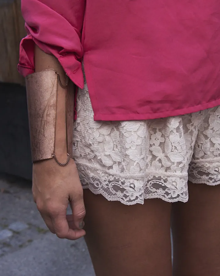Femme arabe entre 25 et 35 ans, en haut noir, se tenant près d'un canapé blanc dans un salon lumineux.